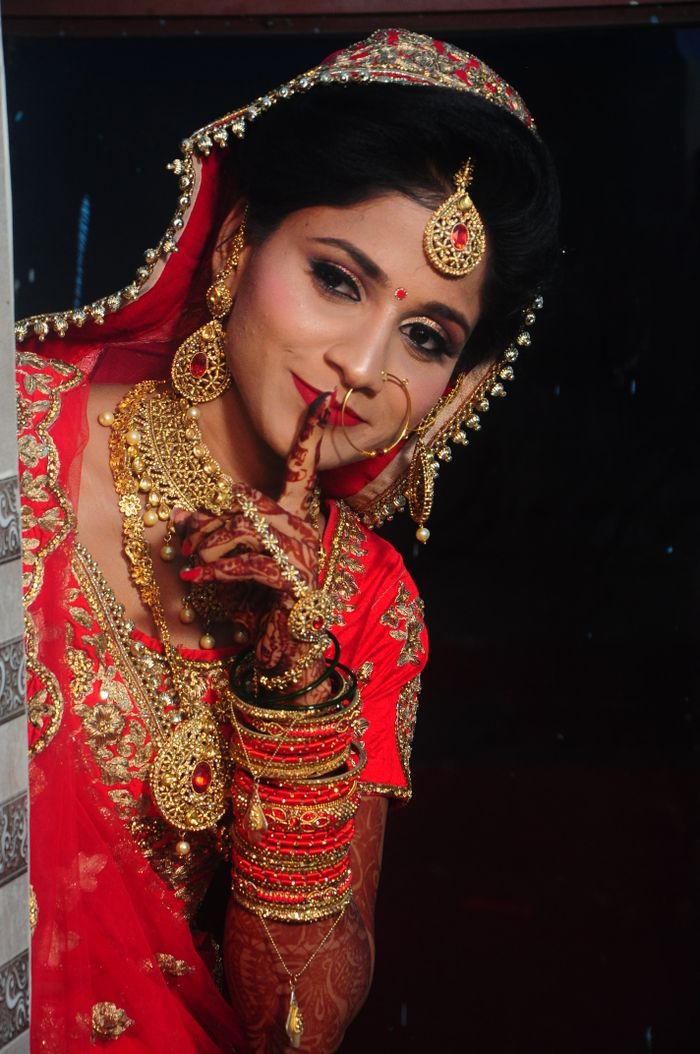 contact-img Beautiful Indian bride adorned in gold jewelry and red saree, showcasing traditional elegance.