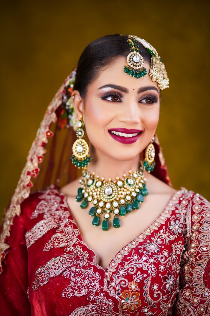 services-03 Beautiful Indian bride in red sari with stunning jewelry and intricate embroidery.