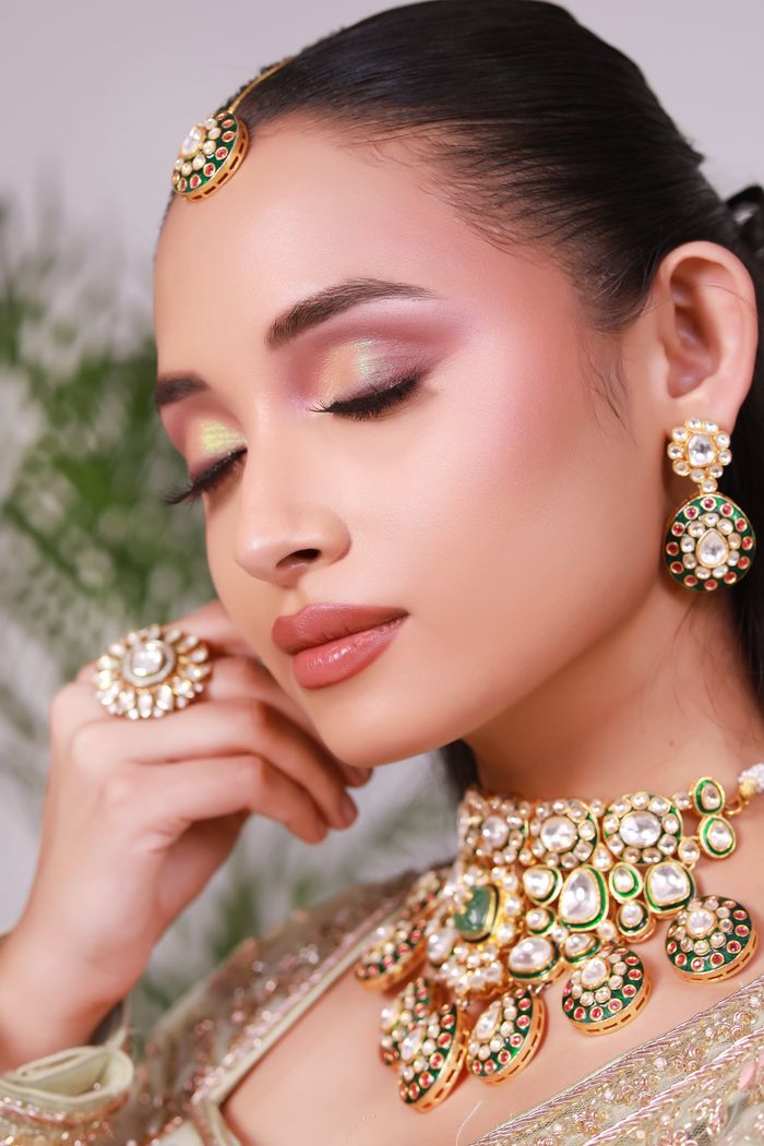 about-01 Close-up portrait of an elegant Indian bride showcasing traditional jewelry and makeup.