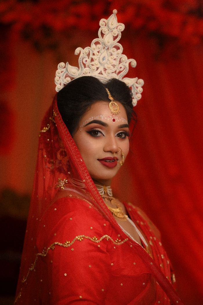 gallery-4 A beautiful bride in traditional red attire with intricate jewelry and a decorative crown.