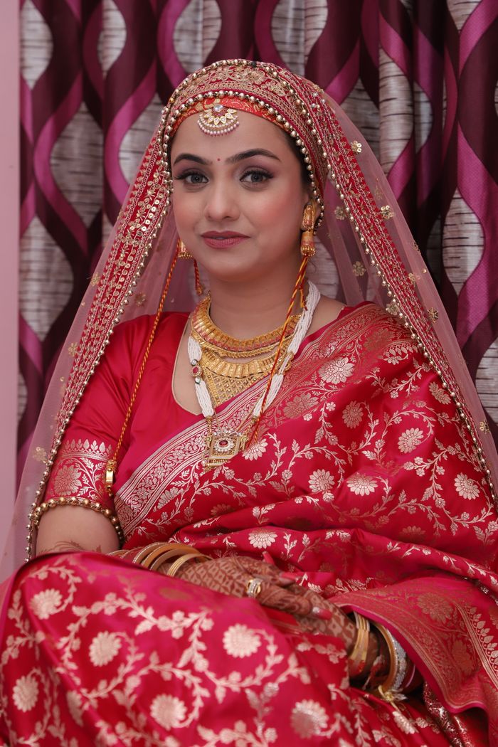 gallery-3 A beautiful Indian bride in a vibrant red saree with intricate jewelry and henna, captured indoors.
