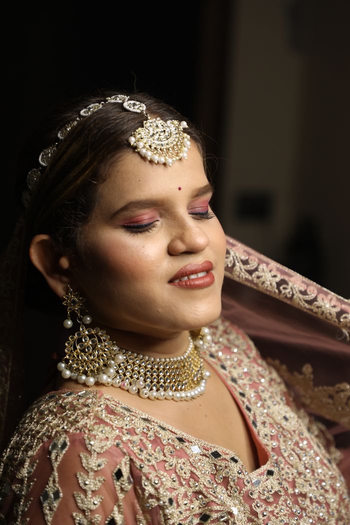 gallery-2 Portrait of a woman wearing intricate traditional bridal jewelry and attire, smiling.