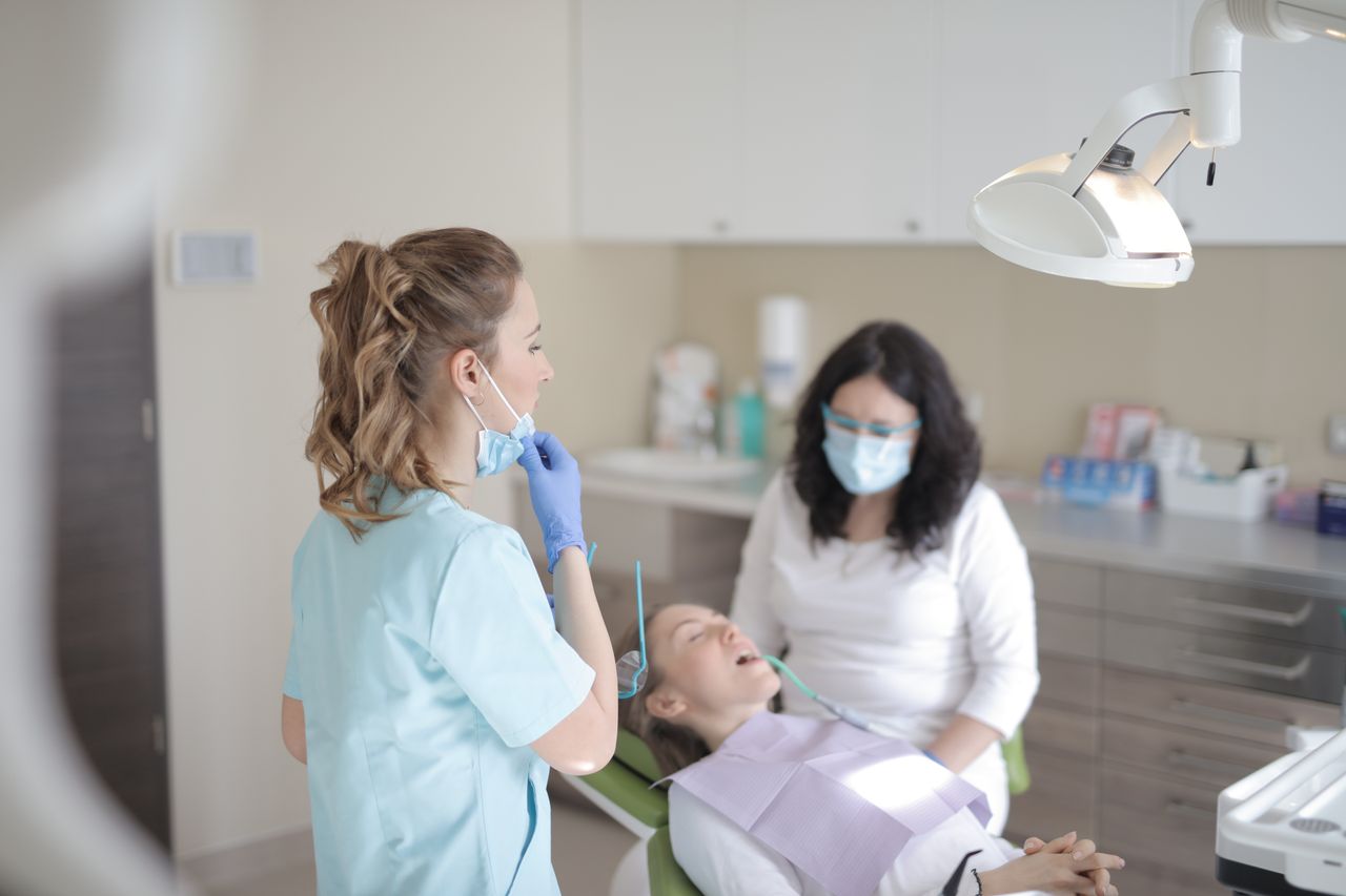 Mastering the First Impression: Your intriguing post title goes here Professional female dentists in mask and gloves curing teeth of patient while working in dental room of modern clinic
