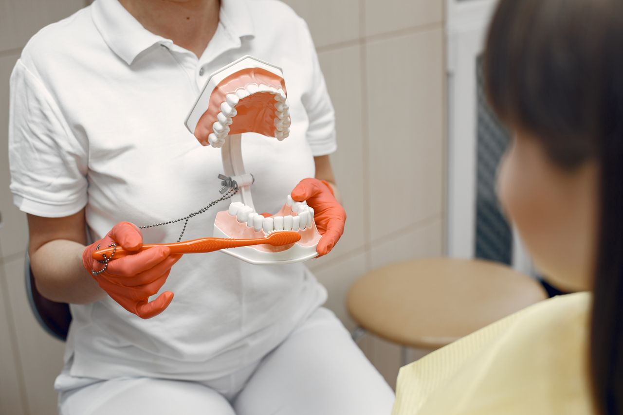 Crafting Captivating Headlines: Your awesome post title goes here A dentist shows proper brushing technique using a dental model to a patient in a clinic.