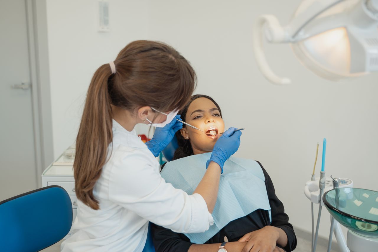 heros-img Dentist conducting a dental examination on a patient in a modern clinic setting.