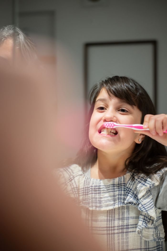 Young girl practicing daily oral hygiene by brushing her teeth indoors.
